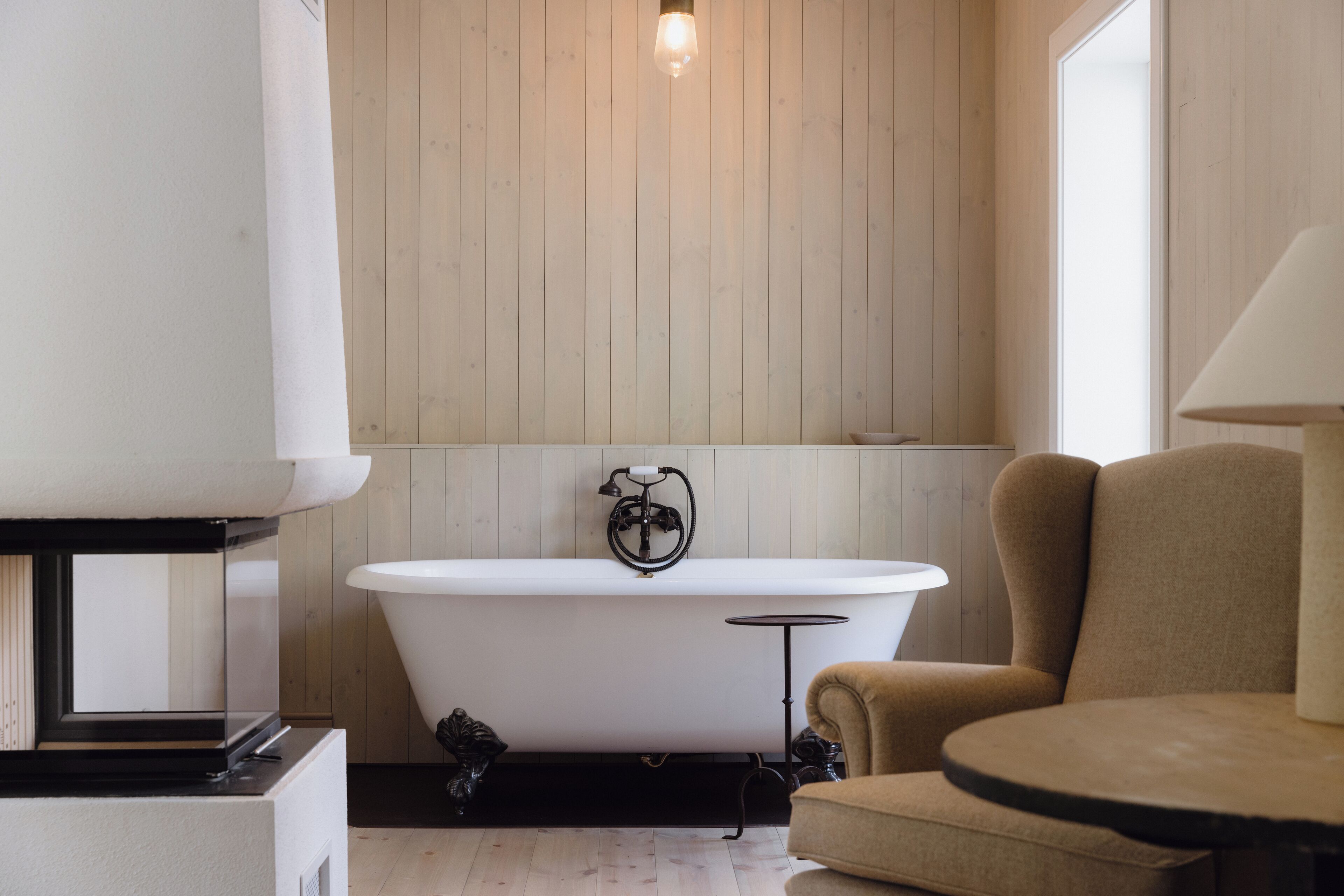 A modern bathroom with a freestanding bathtub, a round table, and a chair.