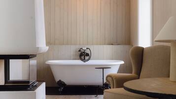 A modern bathroom with a freestanding bathtub, a round table, and a chair.