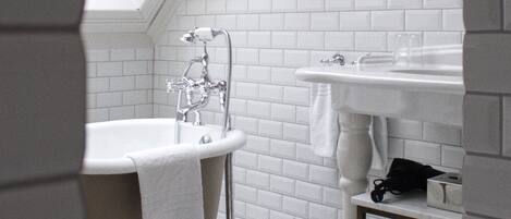 A bathroom with a freestanding bathtub, a sink, and a mirror.