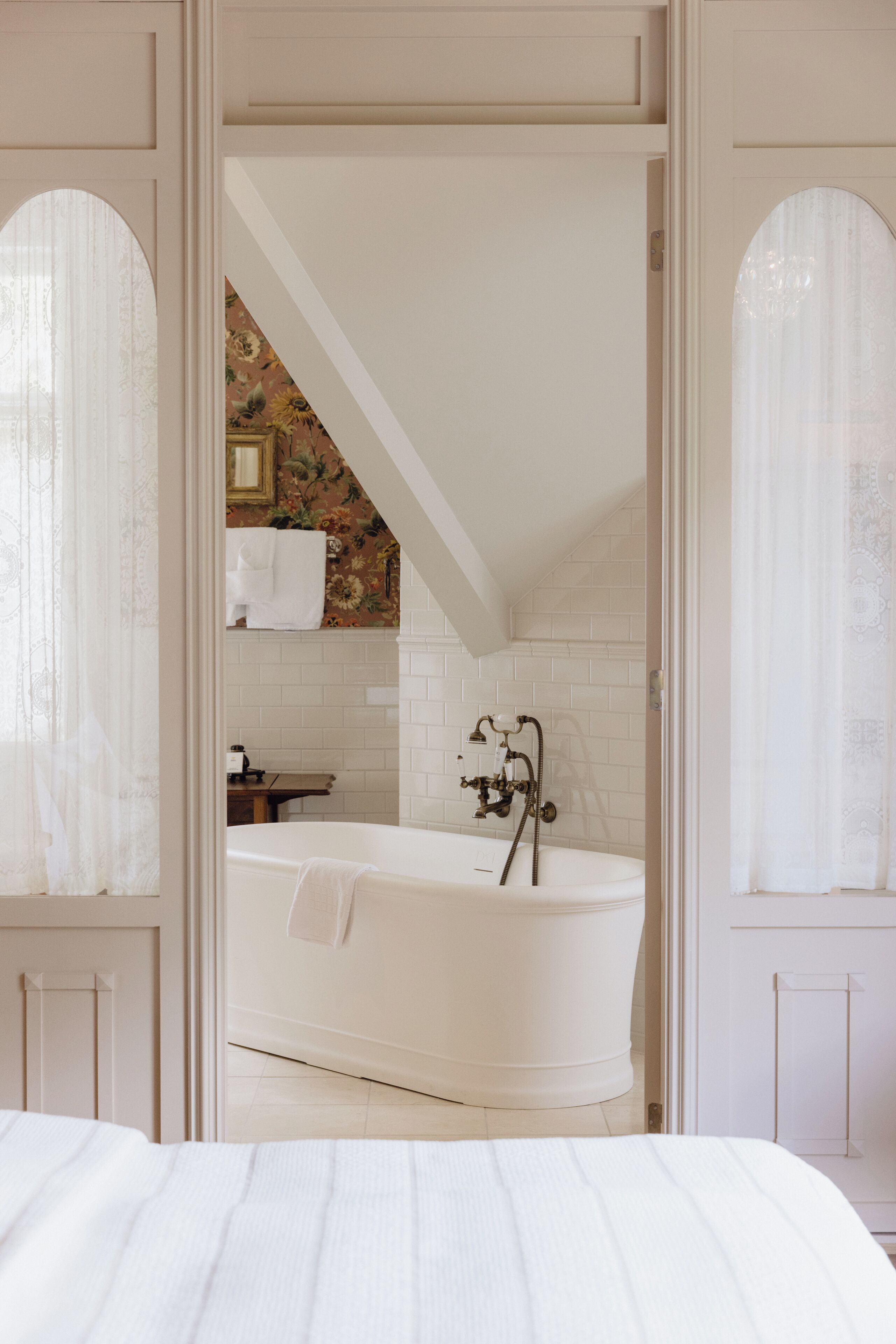 Een slaapkamer met een groot bed, een witte badkuip en een badkamer zichtbaar door een open deur.
