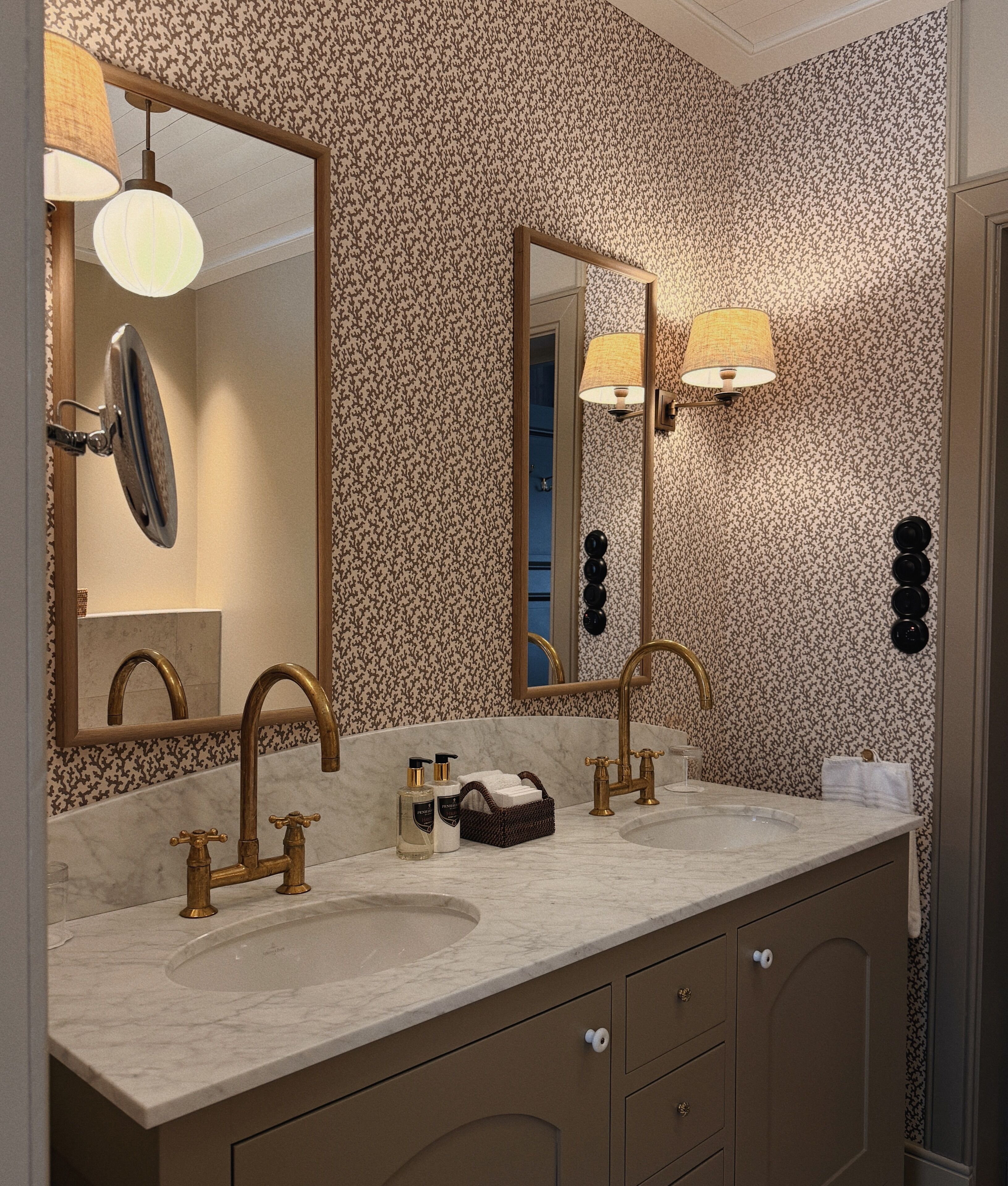 A bathroom with two sinks, a large mirror, and a wall-mounted light fixture.