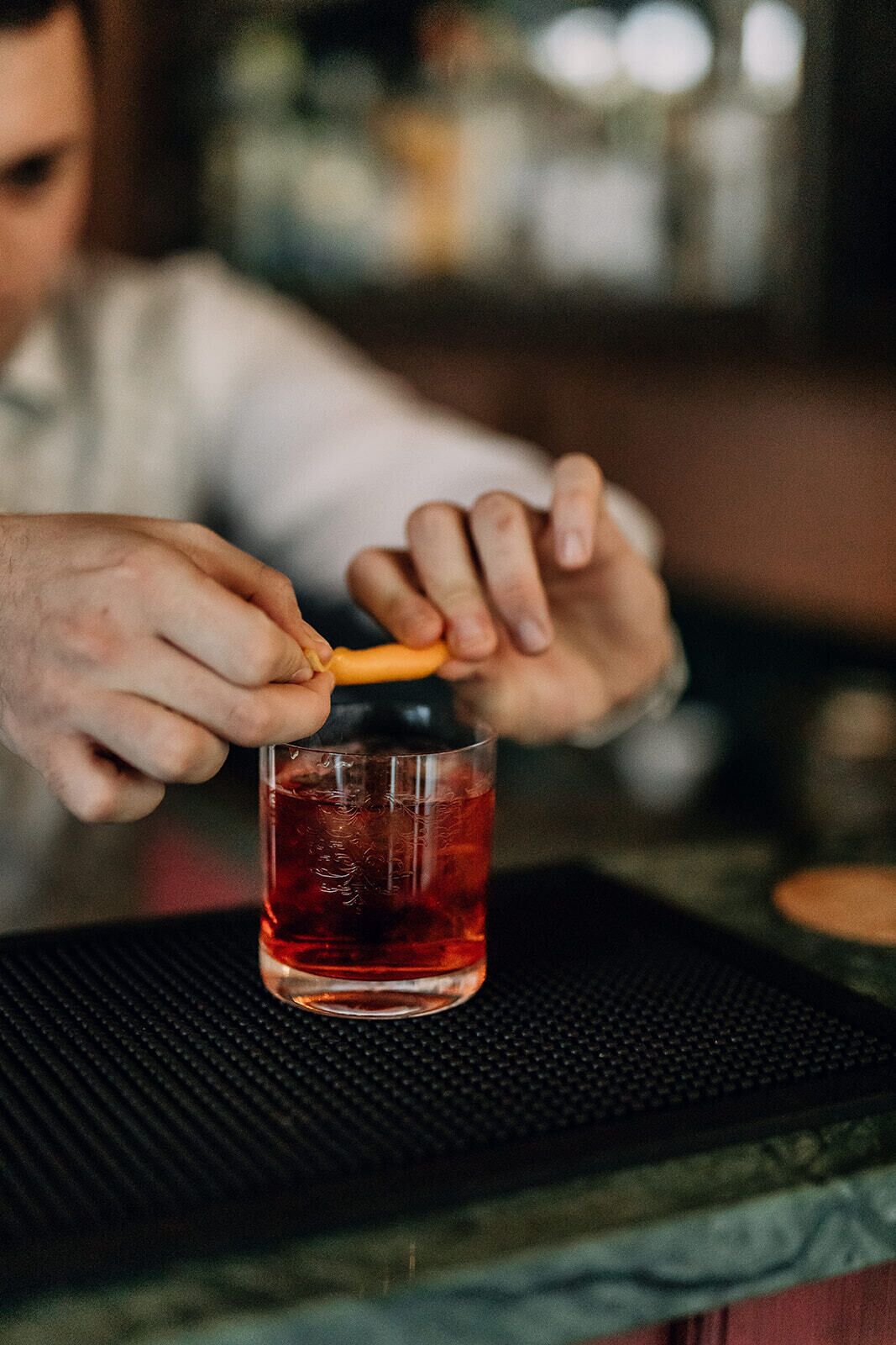 A person pouring a dark liquid from a bottle into a glass.