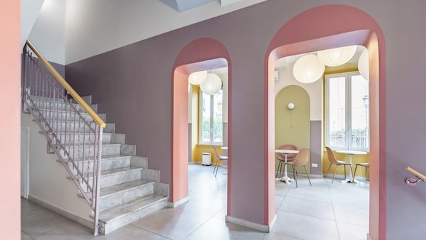 A modern interior with a staircase, arched doorways, and a dining area with chairs and tables. - Hotel Infinito (Rome)