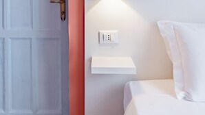 A room with a white door, a wall-mounted light, and a white bedside table. - Hotel Infinito (Rome)