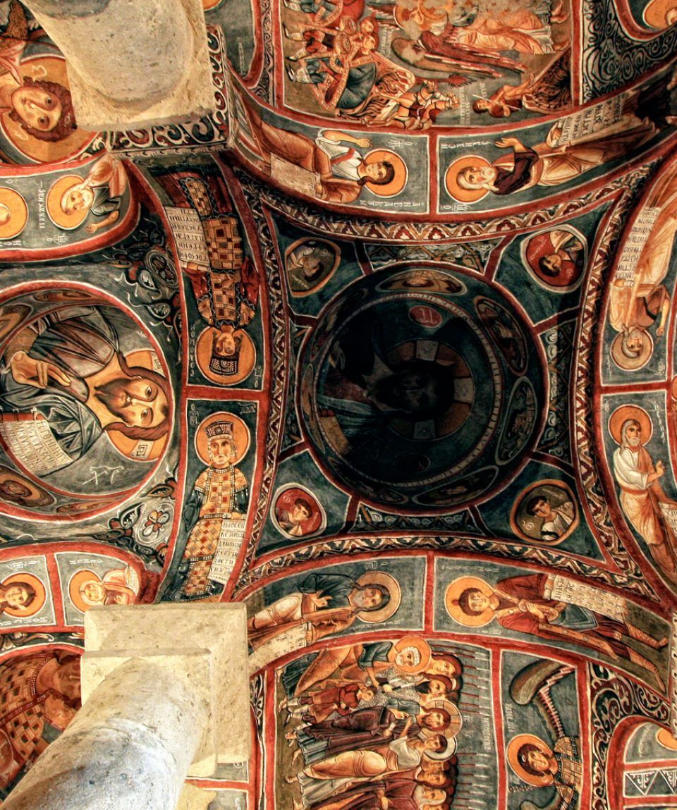 Un detallado fresco en el techo con figuras y símbolos religiosos.