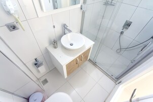 A modern bathroom with a white sink, mirror, and shower.