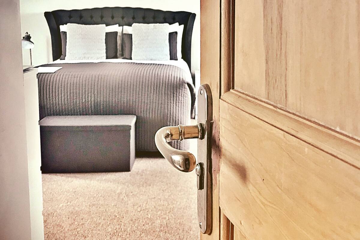 A bedroom with a bed, a bedside table, and a wooden door.