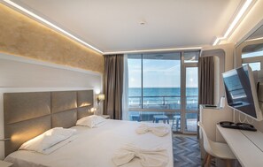 A hotel room with a large bed, a desk with a computer, and a view of the ocean. - Hotel Sunny Bay (Pomorie)