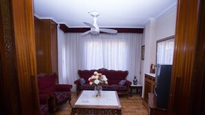 Una sala de estar con ventilador de techo, un juego de sofá, una mesa de centro y televisor.