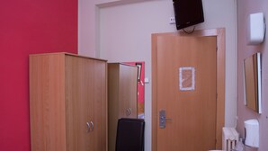 Un baño con un armario de madera, una silla negra, un lavamanos y un ventilador de techo.