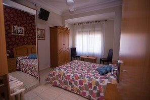 A bedroom with a bed, a desk, a chair, a wardrobe, and a television. - Hostal Navarra (Zaragoza)