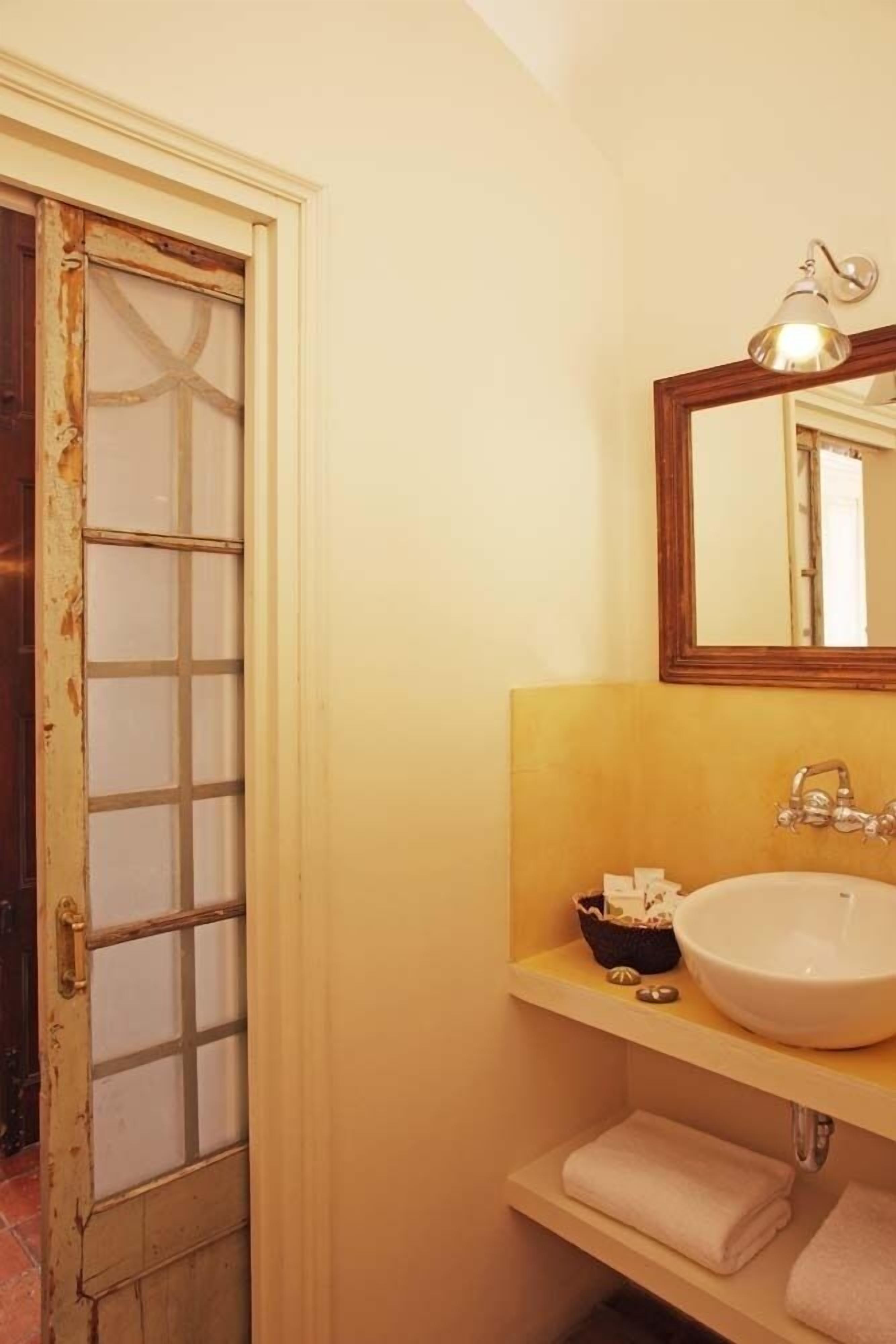 Un baño con un lavabo blanco, un espejo y un perchero para toallas.