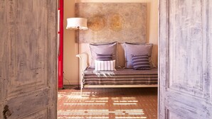 Un dormitorio con cama, almohadas, una lámpara y una obra de arte en la pared.