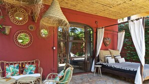 Una habitación con una cama, muebles de mimbre y espejos decorativos.