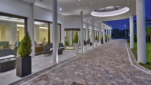 Un moderno vestíbulo de hotel con un camino de ladrillo, zonas de descanso y una entrada de vidrio.