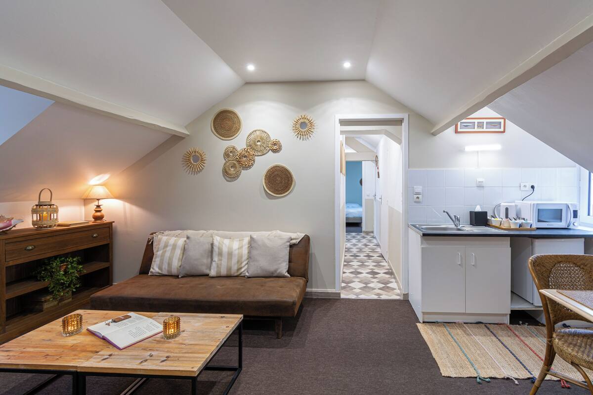 A cozy loft apartment with a loft bed, a kitchenette, a dining area, and a living room.