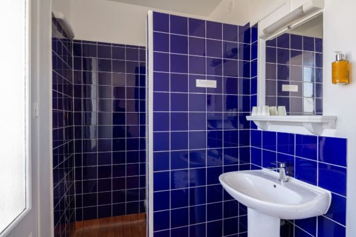 Un baño con azulejos azules, un lavabo blanco y un espejo.