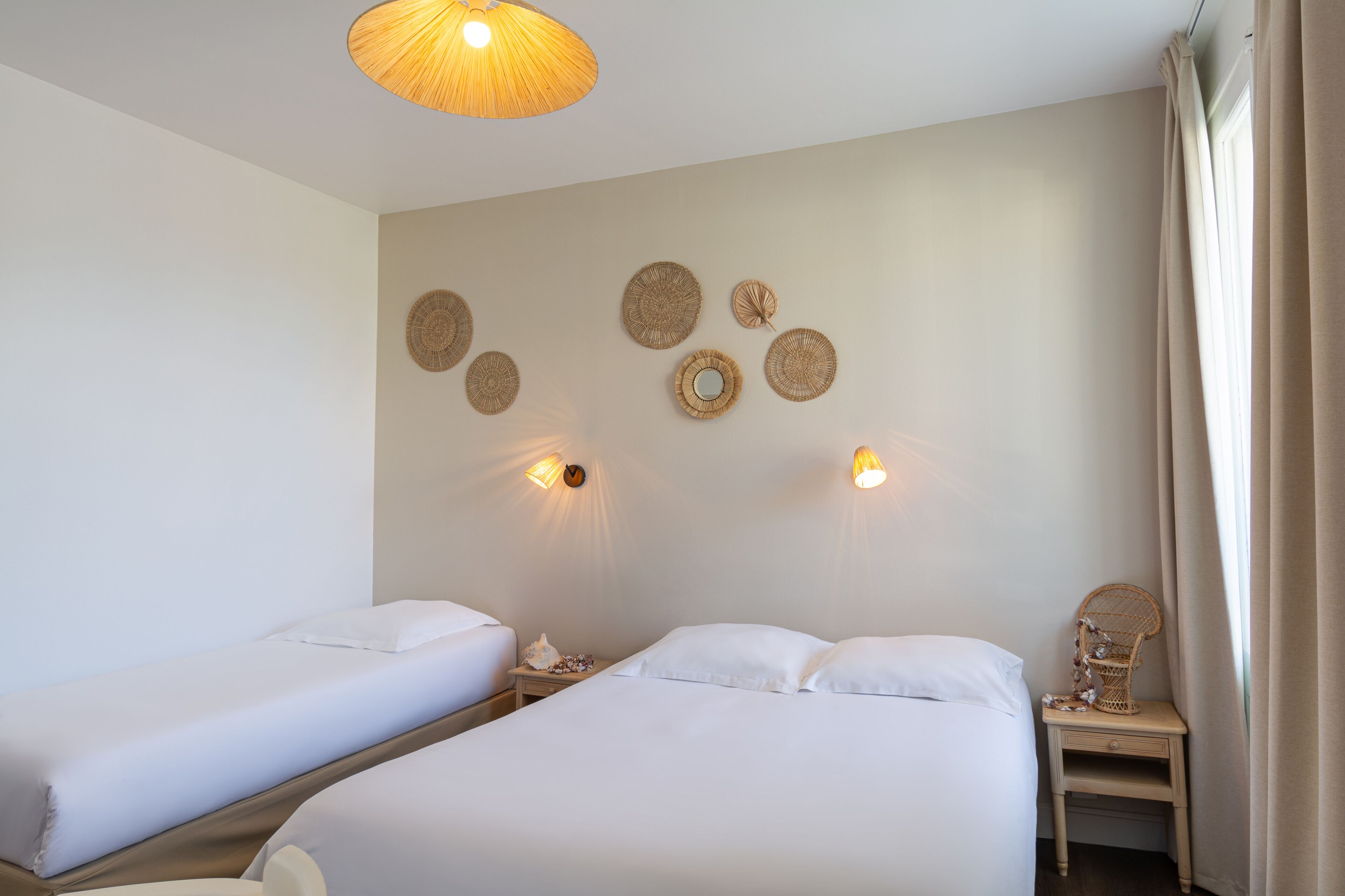 Una camera d'albergo con due letti, un comodino con una lampada e decorazioni a parete.