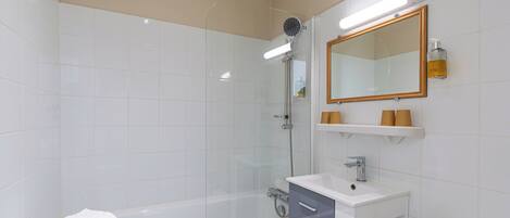 A modern bathroom with a glass-enclosed shower, a white sink, and a toilet.