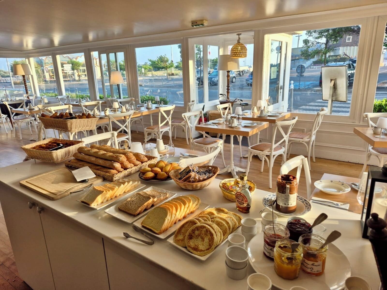 A breakfast buffet with various breads, pastries, and spreads.