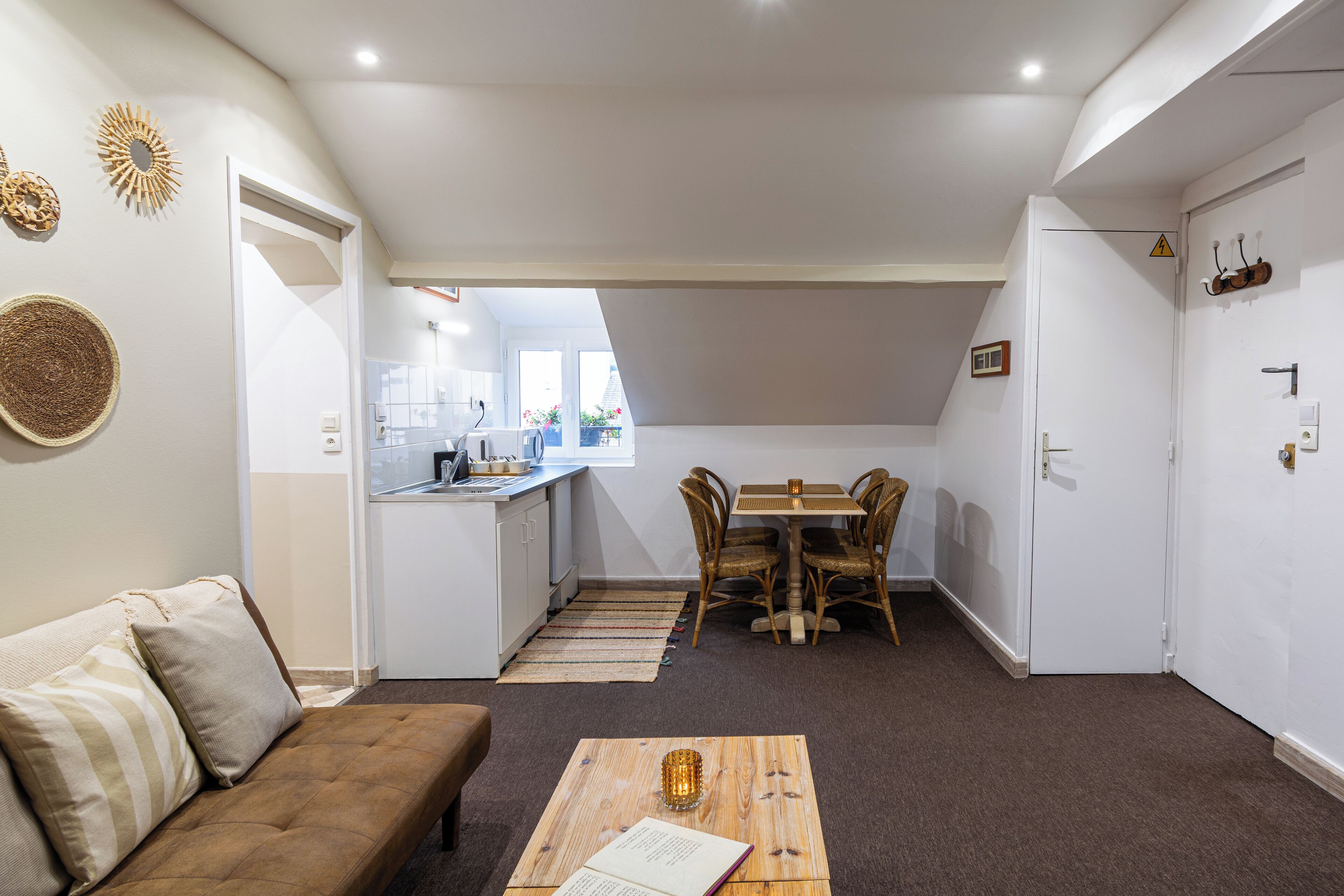 A compact living space with a sofa, a dining table with chairs, a kitchen area, and a small balcony.