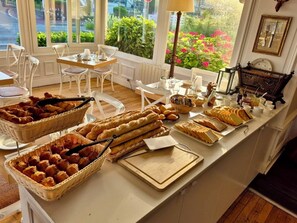 A breakfast buffet with bread, pastries, and beverages.