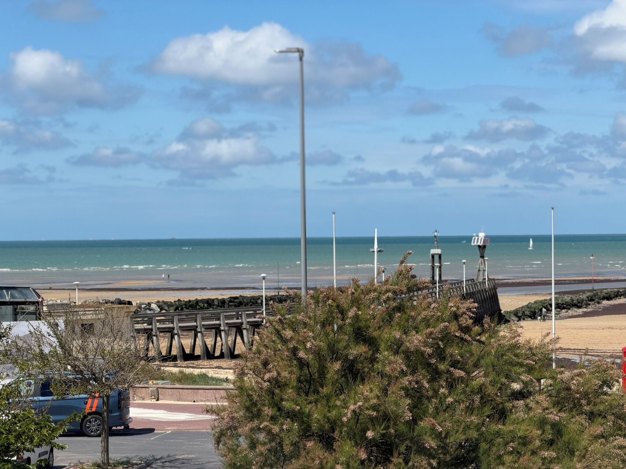 Vista costera con muelle de madera, cielo despejado y el océano al fondo.