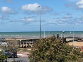 Vista costera con muelle de madera, cielo despejado y el océano al fondo.