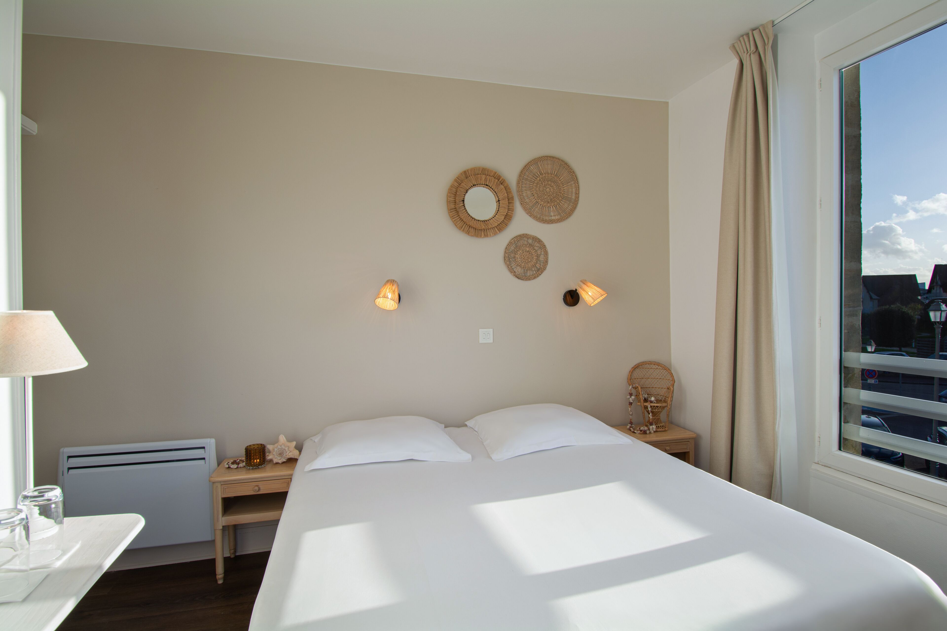 A hotel room with a bed, bedside table, lamp, and wall decorations.