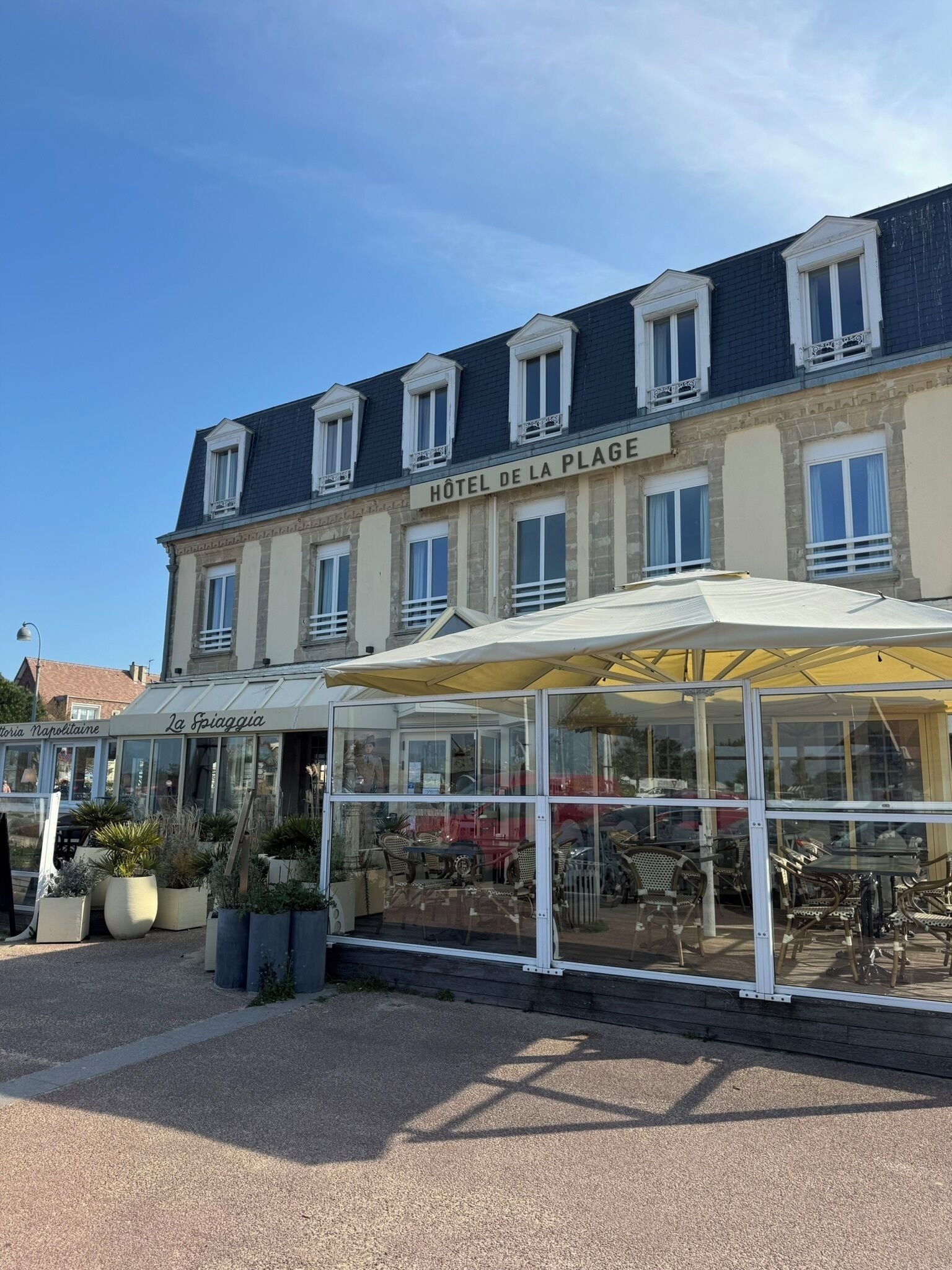 A hotel with a covered outdoor seating area and a clear view of the street.