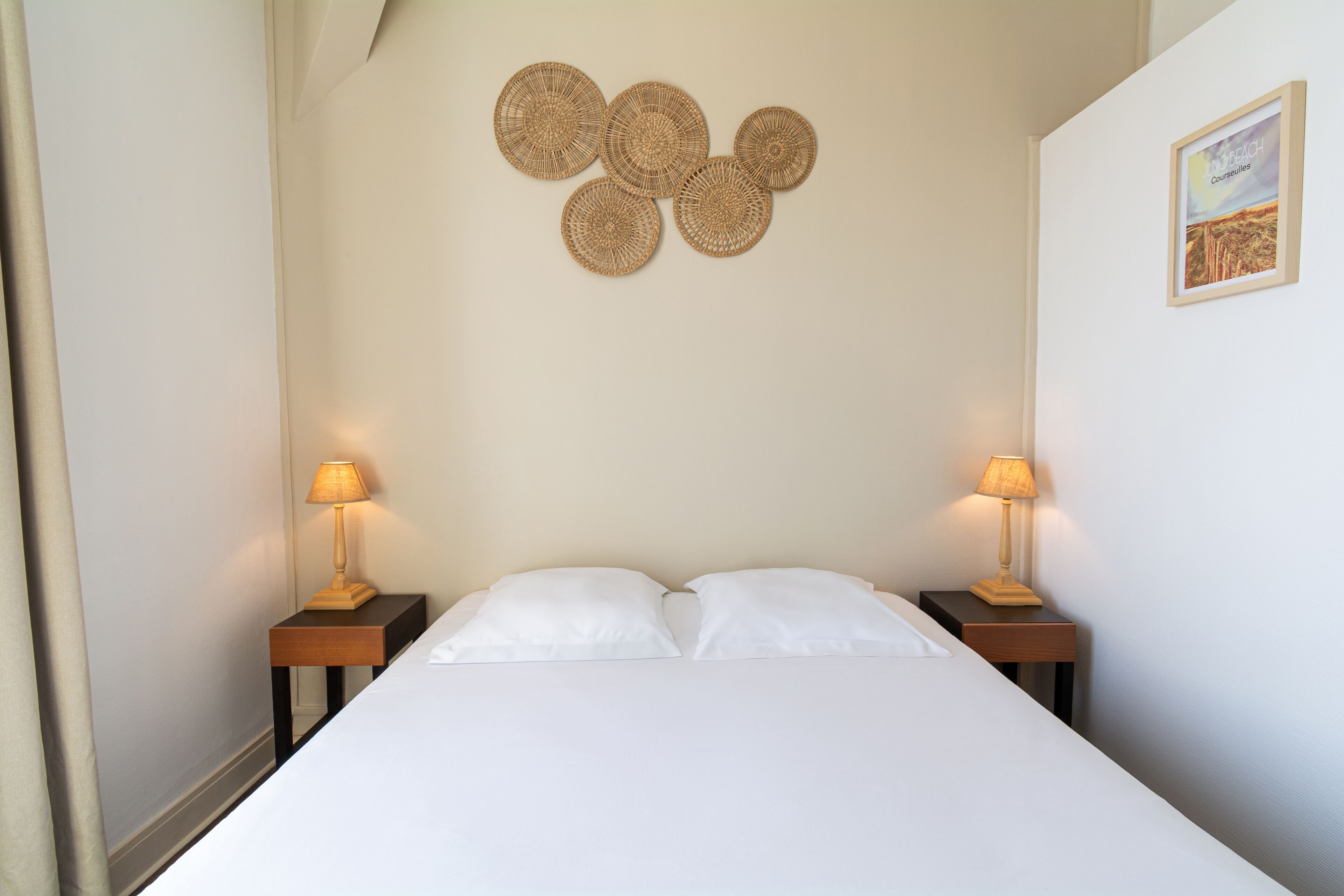A neatly made bed with two white pillows and two nightstands with lamps.