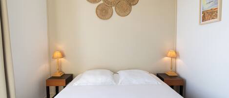 A neatly made bed with two white pillows and two nightstands with lamps.