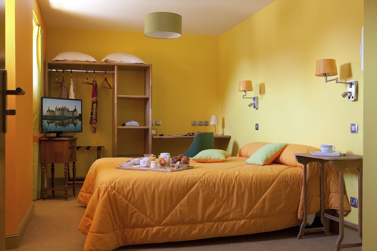 Ett hotellrum med en säng, ett skrivbord, en stol, en tv och en garderob.