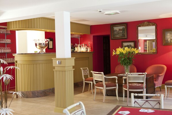 A hotel lobby with a bar area, seating arrangements, and a decorative vase with flowers.