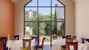 Comedor con mesas dispuestas para una comida, sillas y un amplio ventanal con vistas al exterior.
