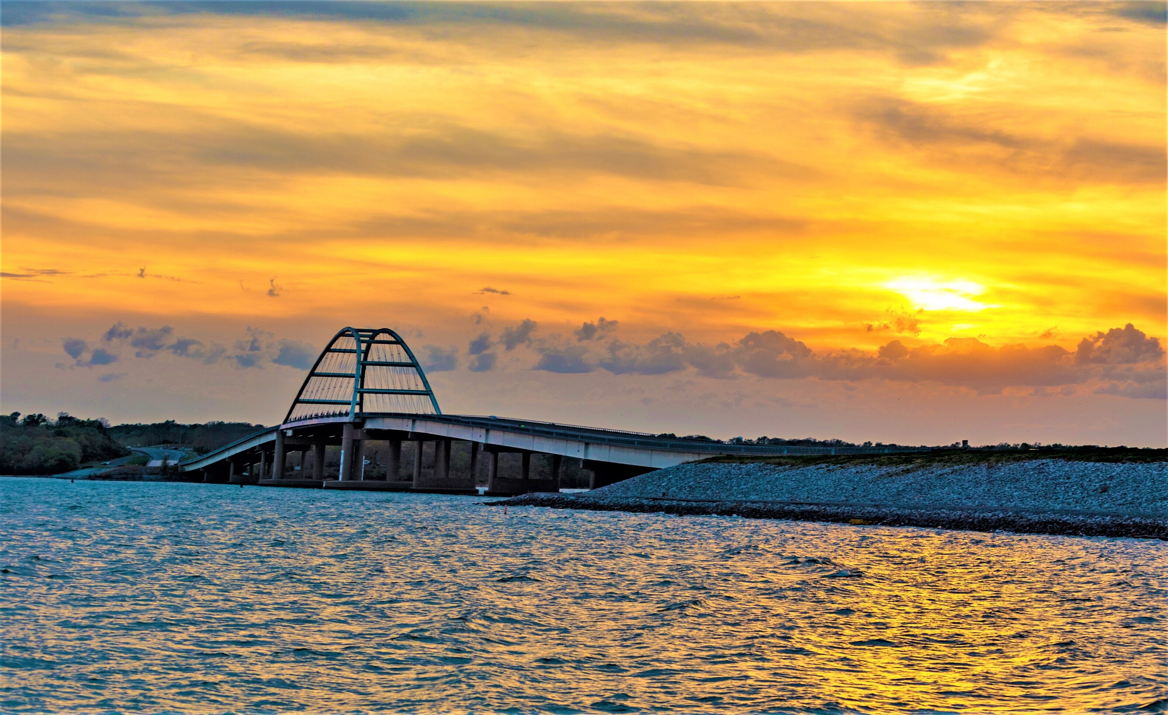 A bridge over water with a sunset in the background.