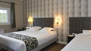 A hotel room with a large bed, two bedside tables, a headboard with a tufted design, and two wall-mounted lamps.