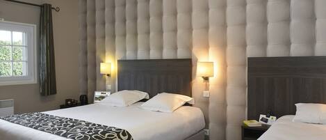 A hotel room with a large bed, two bedside tables, a headboard with a tufted design, and two wall-mounted lamps.