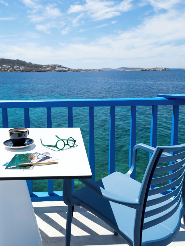 A balcony with a table, a chair, a cup, and a pair of glasses.