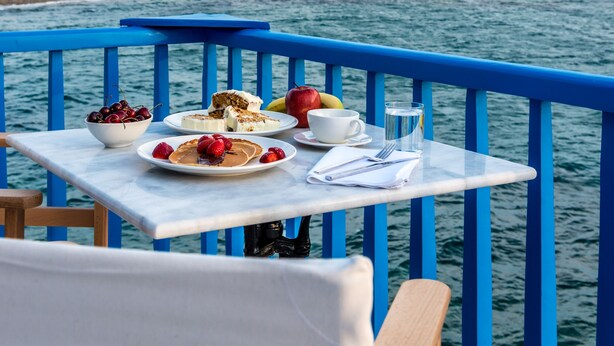 Ein Tisch mit Frühstücksangeboten und Blick auf Windmühlen und Gebäude am Meer.
