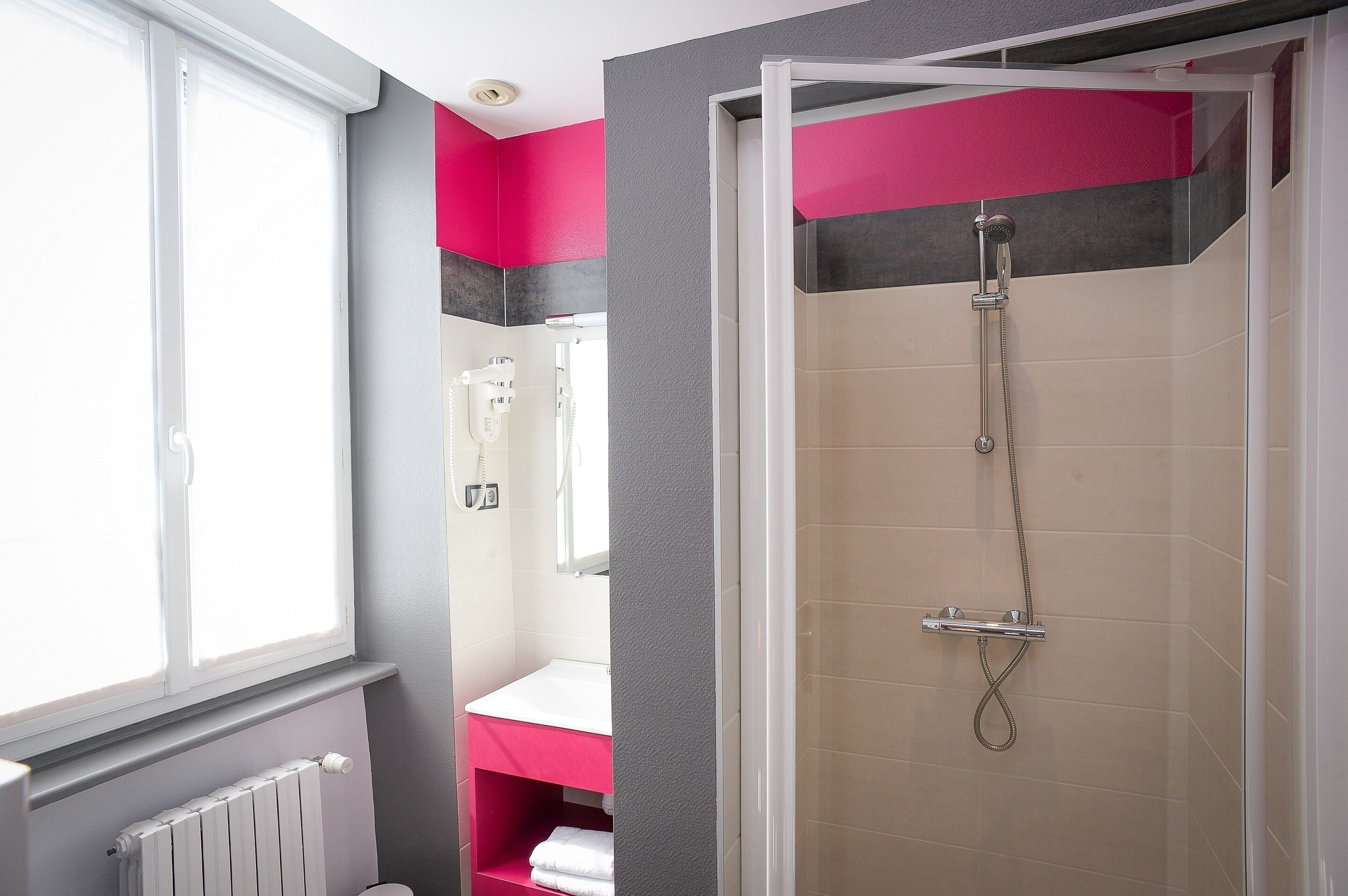 Un baño con ducha, inodoro y ventana.