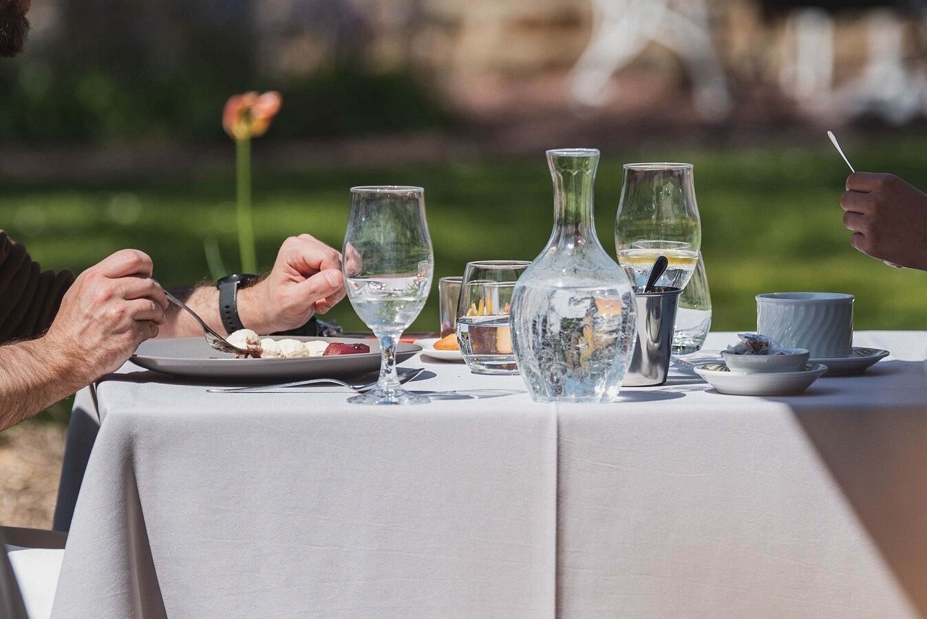 Mesa al aire libre con platos de comida, vasos y una jarra.