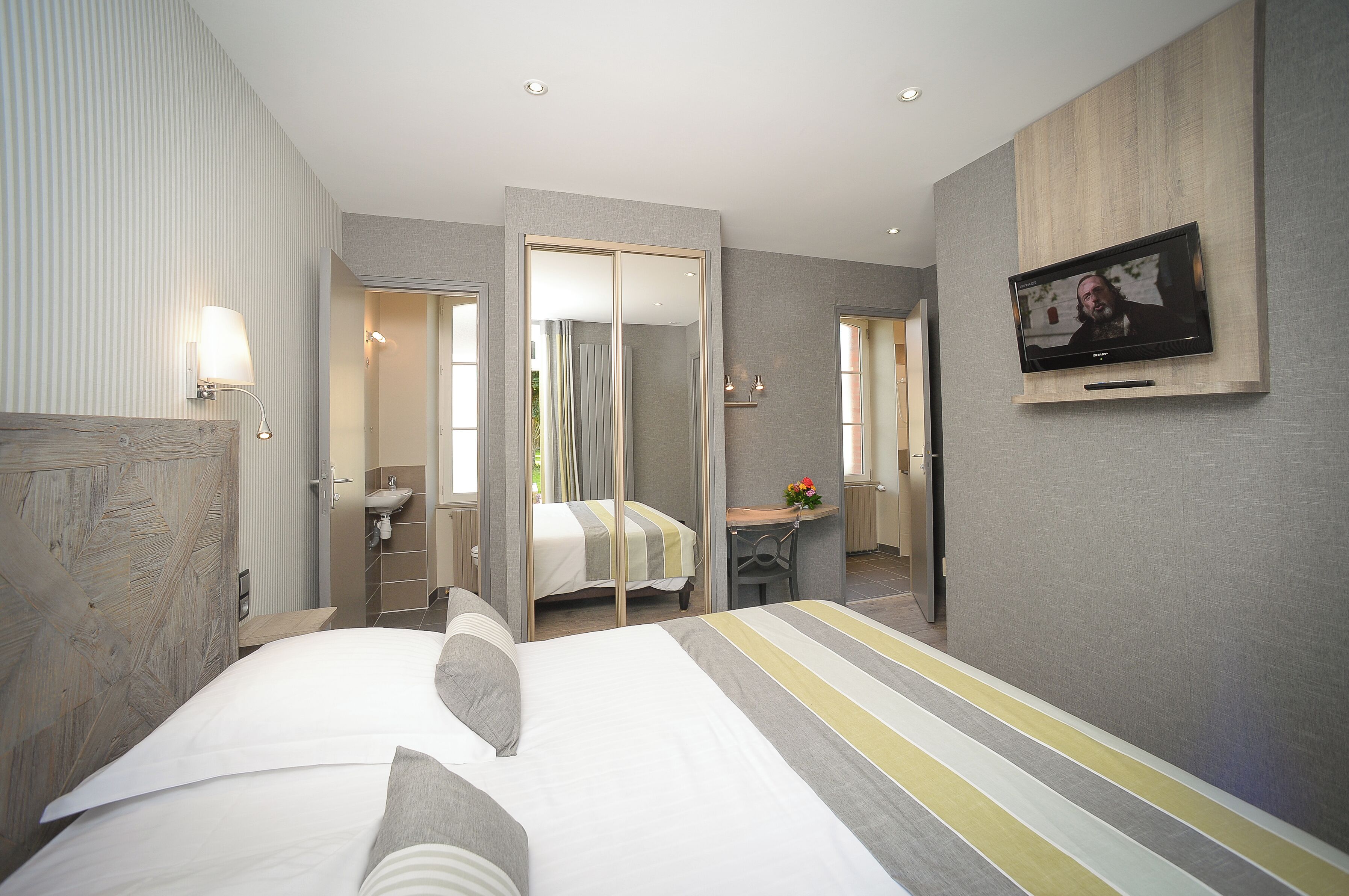 Une chambre d’hôtel moderne équipée d’un grand lit, d’un bureau, d’une télévision et d’une salle de bain avec un miroir.