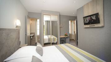 Une chambre d’hôtel moderne équipée d’un grand lit, d’un bureau, d’une télévision et d’une salle de bain avec un miroir.