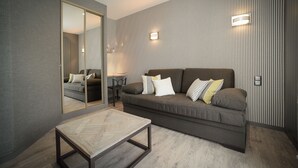 Un salon moderne avec un grand miroir, un canapé avec des coussins, une petite table ronde et une table basse en bois.