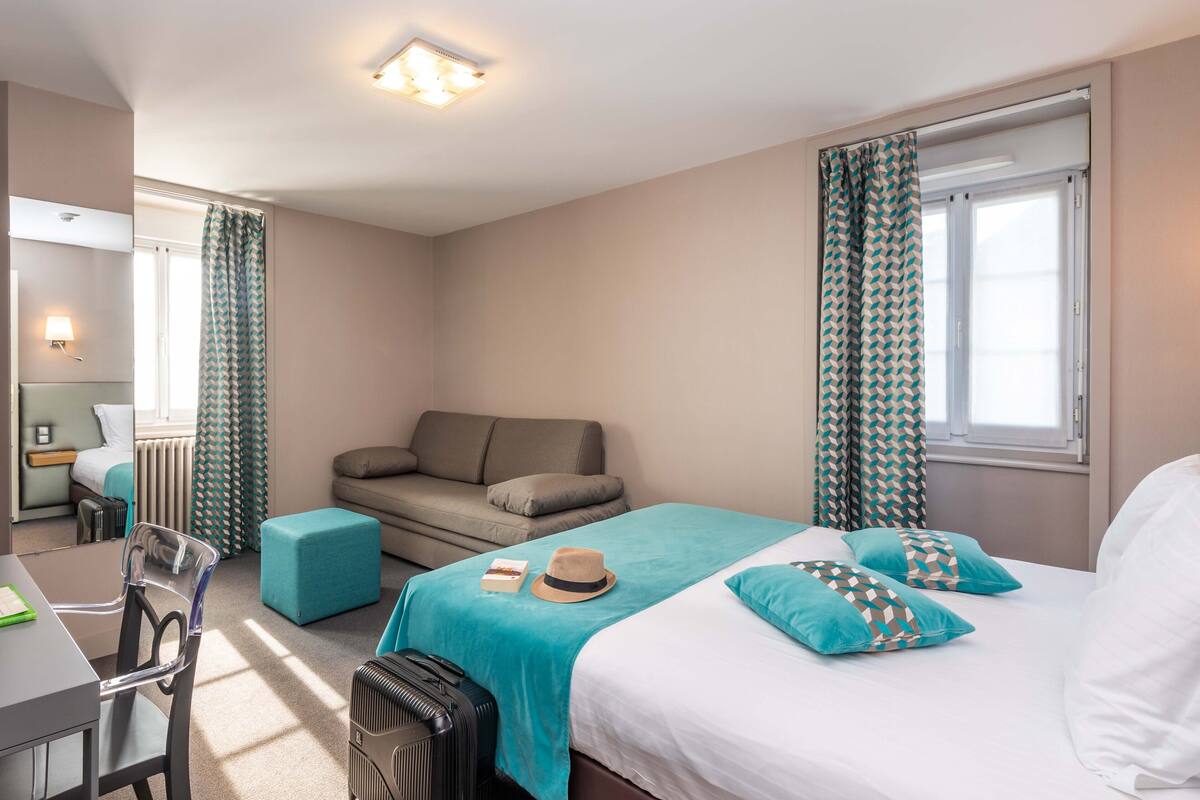 Hotellihuone, jossa on sänky, sohva, työpöytä ja tuoli.