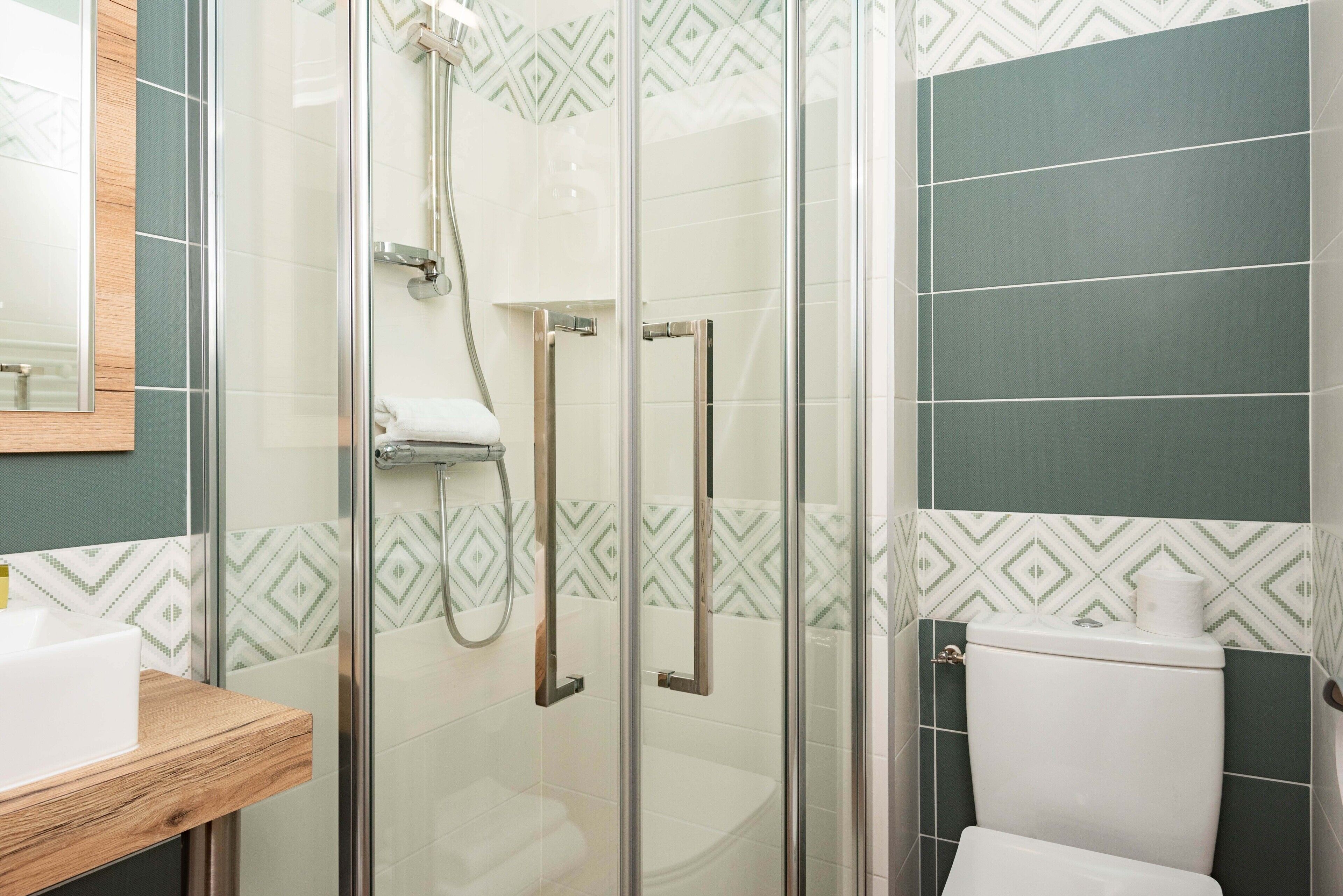 A bathroom with a glass-enclosed shower, a toilet, and a sink.