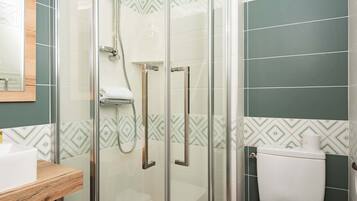A bathroom with a glass-enclosed shower, a toilet, and a sink.
