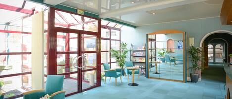 A spacious lobby with a glass partition, seating areas, and a visible outdoor view.