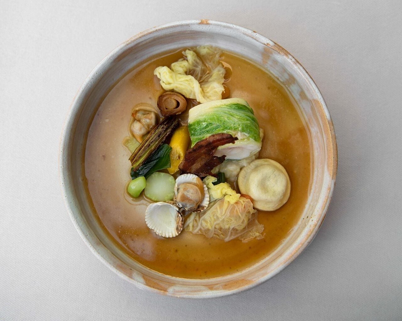 En skål suppe med forskellige ingredienser som kål, muslinger og svampe.